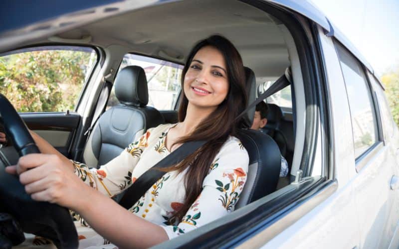 A female driving a car smiling