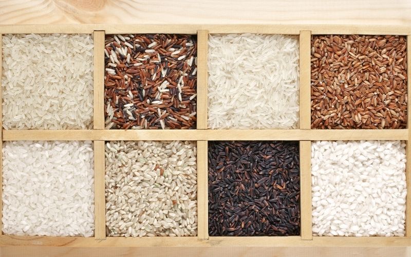 Photo of different kinds of rice in a wooden container