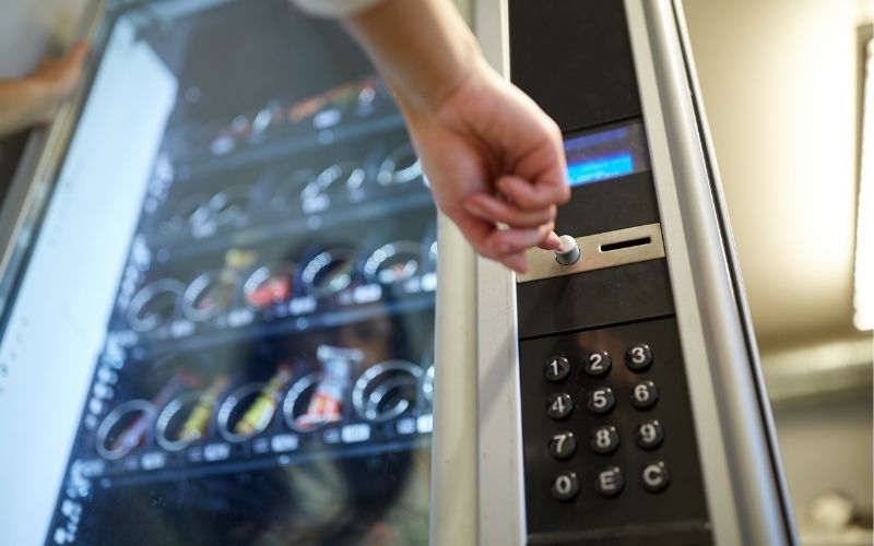 hand pushing button on vending machine